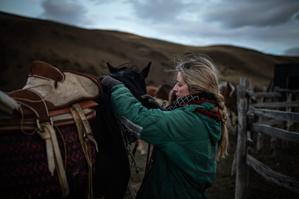 british girl saddling up horse at baguales
